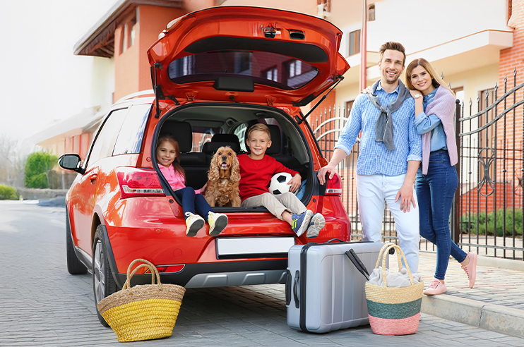 Família a carregar as malas de viagem no carro a caminho das suas férias.